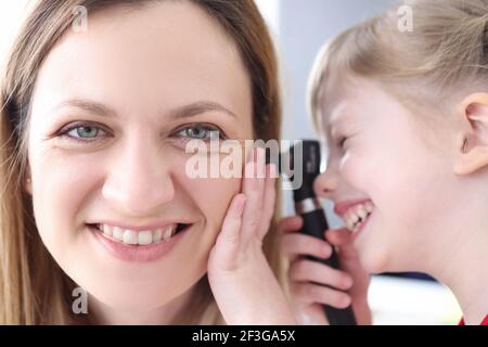 Kleines Mädchen auf das Ohr der Frau Arzt mit Otoskop Stockfoto