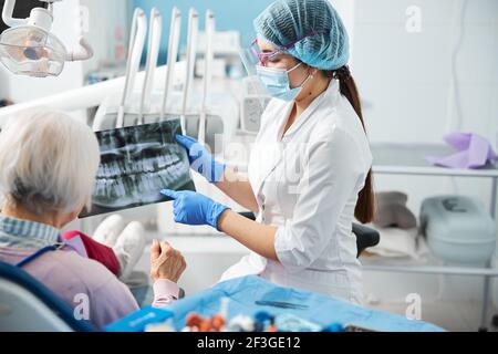 Frau zahnärztlicher Arbeiter zeigt auf Zähne Problem auf Röntgen Stockfoto