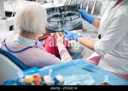 Medizinische Fachärztin zeigt Röntgenaufnahme ihres Klienten mit Zahnbild Stockfoto