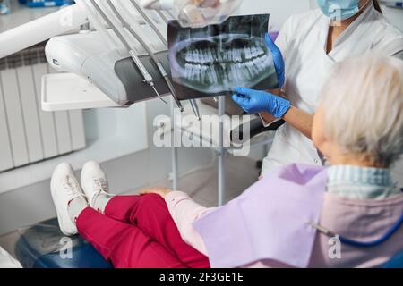 Zahnärztliche Röntgenaufnahme, die von einem Kieferorthopäden in der Nähe des Besuchergesichtes gehalten wird Stockfoto