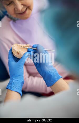 Medizinische Mitarbeiter klopfen mit Dental Explorer auf Zähne gegossen Stockfoto