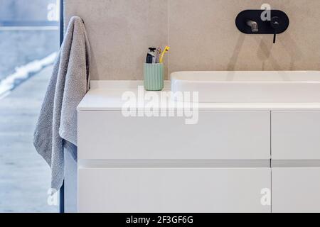 Modernes Badezimmer mit einem weißen Waschbecken auf einer weißen Arbeitsplatte und einem Spiegel darüber. Stockfoto