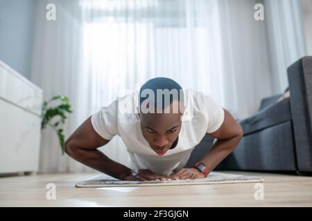 Afroamerikanischer Kerl in weißen Kleidern mit ahome Training Stockfoto