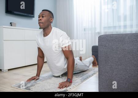 Afroamerikanischer Kerl in weißen Kleidern mit ahome Training Stockfoto