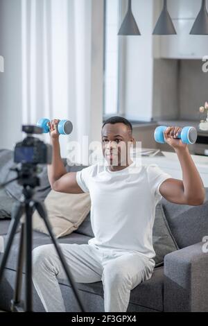 afroamerikanischer junger Mann, der Übungen mit Hanteln vorführt Stockfoto