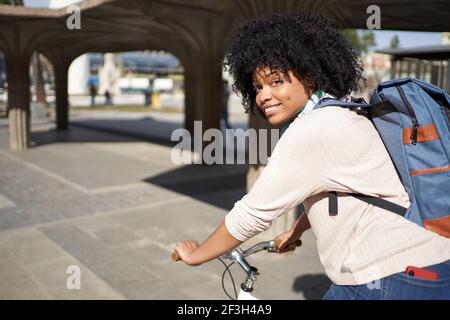 Latina Frau auf dem Fahrrad in der Stadt. Afroamerikanische Frau mit grünen Transport. Hochwertige Fotos Stockfoto