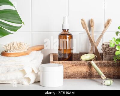 Weiß Bad Hintergrund Vorderansicht mit kosmetischen Flasche, Bad-Accessoires und grünes Blatt auf weißem Regal und Wandfliesen, Stockfoto