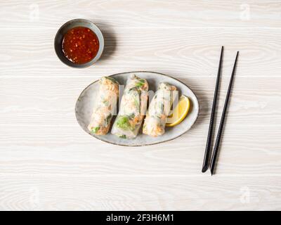 Vietnamesische Frühlingsrollen mit Salat, Sauce, Krabben und Nudeln auf einem ovalen Teller mit würziger Sauce. Draufsicht. Copy space Stockfoto