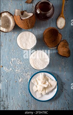 Ein Glas Kokosnussmoothies mit Kokosnuss. Coconut Smoothie vith Scheiben von frischer Kokosnuss und Flocken in Löffel auf Holzhintergrund. Stockfoto