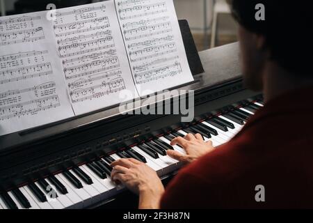 Oben Nahaufnahme der Hände eines nicht erkennbaren Musikers, der zu Hause auf dem Klavier spielt. Stockfoto