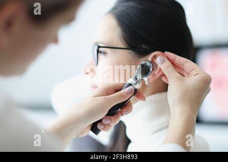 Der Otorhinolaryngologe untersucht das Ohr des Patienten mit einem Otoskop Stockfoto