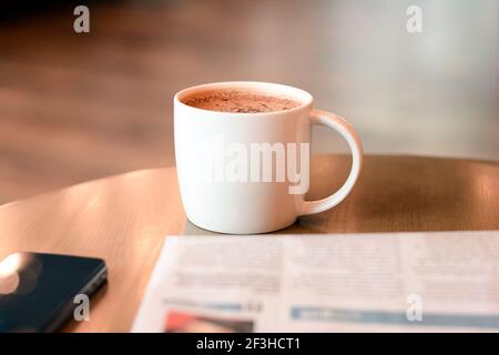 Kaffeetasse mit Zeitung und Handy auf Holztisch Stockfoto