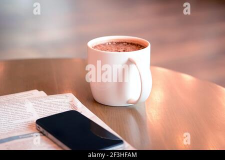 Kaffeetasse mit Zeitung und Handy auf Holztisch Stockfoto