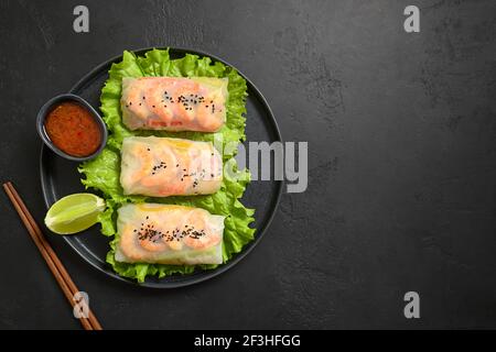 Asiatische Frühlingsrollen mit Garnelen in Reispapier auf schwarzem Stein Hintergrund gewickelt. Blick von oben. Asiatische Küche. Stockfoto