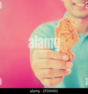 Ein Mann, der gebratenes Hühnerbein oder Drumstick gibt - vintage Style-Farbeffekt Stockfoto