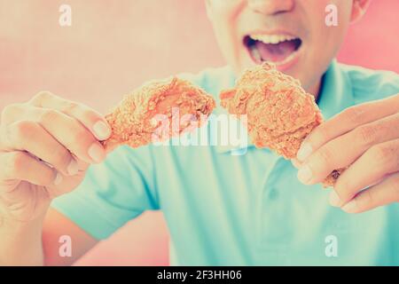 Ein Mann mit Öffnung Mund über frittierte essen Hähnchenbeine oder Drumsticks - Vintage (Retro) Stil Farbeffekt Stockfoto