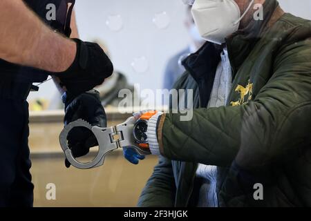 Itzehoe, Deutschland. März 2021, 17th. Ein Justizbeamter (l) nimmt die Handschellen von der Beklagten zu Beginn eines Prozesses wegen Mordes an Itzehoe Landgericht. Die Staatsanwaltschaft wirft dem 41-jährigen Angeklagten vor, am 29. Juni 2020 einen 44-jährigen Mann auf einer Pferdefarm in Quickborn getötet zu haben. Quelle: Christian Charisius/dpa/Alamy Live News Stockfoto