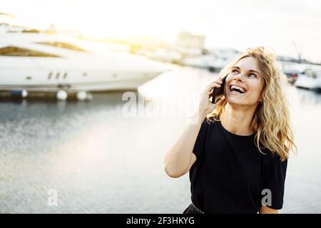 Frau, die im Sommer auf dem Pier steht und telefoniert Tag Stockfoto