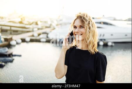 Mädchen, die im Sommer auf dem Pier stehen und telefonieren Tag Stockfoto
