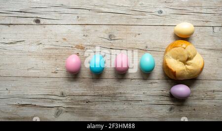 Kleines osterbrot zwickt mit ein paar bunten ostereiern auf Holzhintergrund Stockfoto