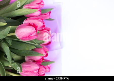 Rosebuds von rosa Tulpen liegen auf einem weißen Tisch. Ein Strauß Frühlingsblumen für einen Urlaub Stockfoto