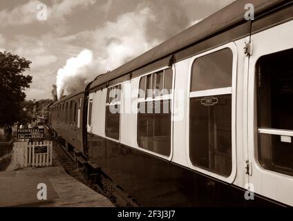 SHEFFIELD PARK STATION, VEREINIGTES KÖNIGREICH - Oct 10, 2012: Sepia-getönte Bild von 1960s Zug, gezogen von einer Dampflokomotive, auf der Bluebell Railway, an She Stockfoto