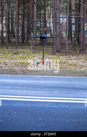 Ein Kreuz am Straßenrand mit einem Motorradhelm zum Gedenken an den tragischen Tod eines Motorradfahrers. Hergestellt an einem bewölkten Tag, weiches Licht. Stockfoto