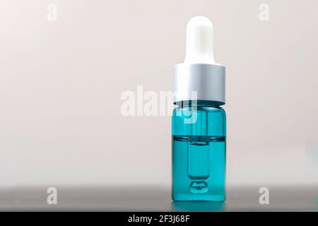 Kosmetische türkisfarbene Flasche mit Pipette auf weißem Hintergrund mit Kopierraum, Makro. Konzept der Kosmetologie, Medizin Stockfoto
