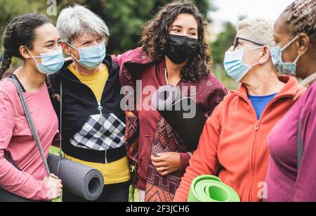 Multi-Generationen-Frauen, die Spaß vor Yoga-Klasse tragen Sicherheit Masken während Coronavirus Ausbruch im Park Outdoor - Sport und Soziale Distanz Kontra Stockfoto