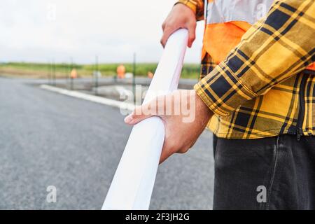 Bauarbeiter mit Entwicklungsplan oder Baustellenplan auf dem Baustelle Straßenbau Stockfoto