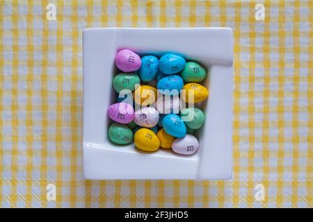 Schüssel mit M&M's Eggs Schokolade auf gelb-weiß karierten Gingham Servietten M&ms Eggs Stockfoto