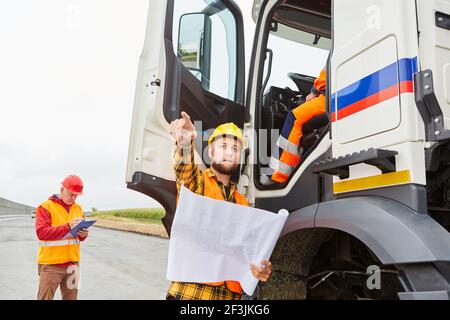 Bauarbeiter als Vorarbeiter im Straßenbau geben LKW-Fahrer Anweisungen auf der Baustelle Stockfoto