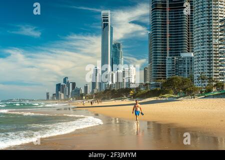 Surfers Paradise, Gold Coast, Australien - Menschen, die am Strand entlang laufen, mit Hochhäusern im Hintergrund Stockfoto