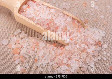 Rosa himalaya-Salz. Nahaufnahme Himalayan Pink Rock Salt in Holzlöffel auf schwarzem Hintergrund. Draufsicht. High Angle View Of Himalayan Salt With Wooden Sp Stockfoto