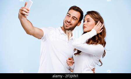 Junges Paar nimmt Selfie isoliert auf blau Stockfoto