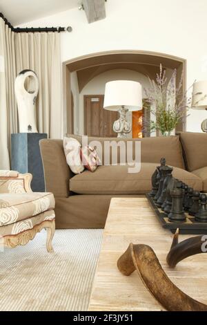 Hörner und Riesenschach auf Couchtisch mit Lampe auf Tisch, eingerahmt von Torbogen, der zur Halle im Hintergrund führt Stockfoto