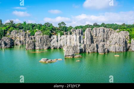 Kalksteinfelsen Formation über schönen See und blauen Himmel an Shilin Stein Waldpark in Yunnan China Stockfoto