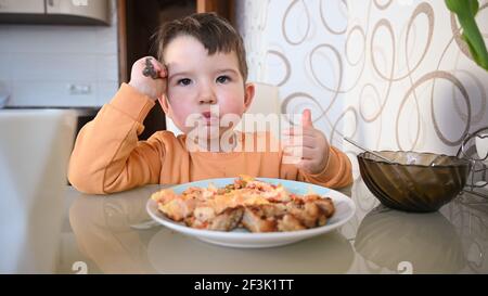 Das Kind isst alleine am Tisch. Hochwertige Fotos Stockfoto