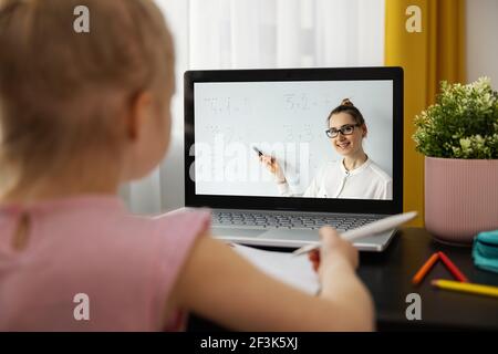 Fernunterricht - Grundschullehrerin erklärt grundlegende Mathematik online. Kleines Mädchen mit Laptop zu Hause. Matheunterricht Stockfoto