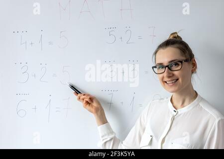 Mathe Lehrer erklärt Grundschule grundlegende Mathematik auf Whiteboard in Schulungsraum Stockfoto