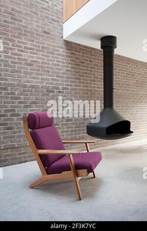 Duggan Morris Haus: Kings Grove, Peckham, London. Foto zeigt den Hauptwohnbereich mit dem hängenden Kamin und Designer-Stühlen Stockfoto