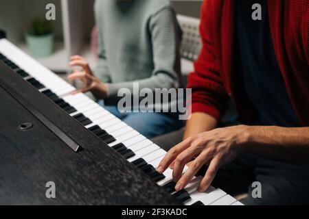 Nahaufnahme eines Jungen, der Klavier spielt, Musiklehrer sitzt in der Nähe und hilft beim Spielen während des Unterrichts. Stockfoto