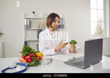 Ernährungsberaterin spricht über die Vorteile von Brokkoli für ihre Patientin während einer Online-Konsultation. Stockfoto