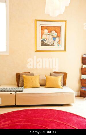 Luxuriöses Wohnzimmer Bereich, Zeitgenössisches sauberes Design mit runden roten Teppich. Gelbe Seiden Kissen, Zeitschriftenständer und moderne Malerei. Stockfoto