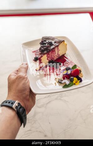 Eine vertikale Aufnahme einer köstlichen Scheibe verbrannter Käsekuchen Mit Beeren in einem Restaurant serviert Stockfoto