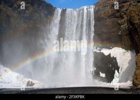 Regenbogen und Schnee über dem Skogafoss Wasserfall, Süd-Island Stockfoto