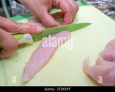 Ein selektiver Fokus Schuss von Händen schneiden Hähnchenfilets mit Ein Messer auf einem Schneidebrett Stockfoto