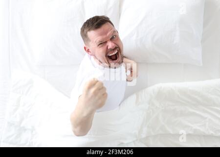 Junger Mann liegt im Bett und freut sich von oben Stockfoto