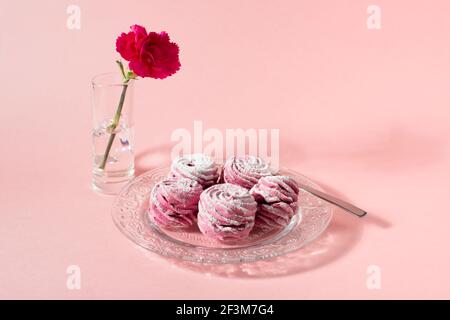 Rosa Marshmallow Cupcakes auf rosa Hintergrund. Und rosa Nelkenblume. Speicherplatz kopieren. Stockfoto