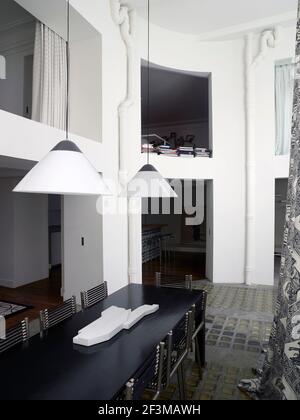Offener Essbereich mit Blick auf die oberen und unteren Zimmer auf zwei Ebenen mit Tischstühlen und hängenden Lampen in einem französischen Wohnhaus. Stockfoto